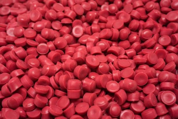 Close-up of red thermoplastic elastomer pellets, safe and free from harmful additives.