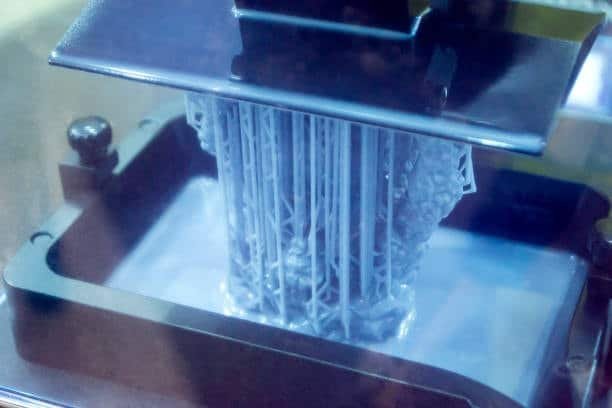 SLA printer curing resin layer-by-layer and lifting a detailed structure from the vat.