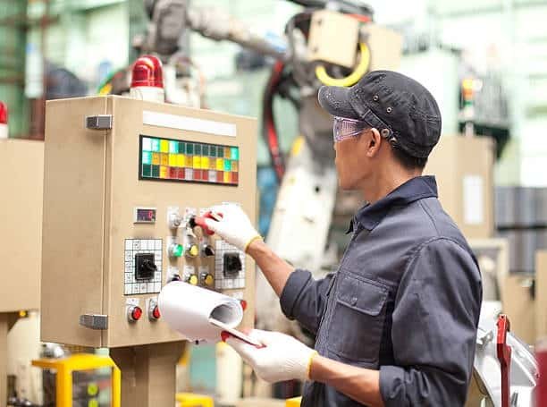 Factory technician programming control panel for automated inspection settings on industrial equipment