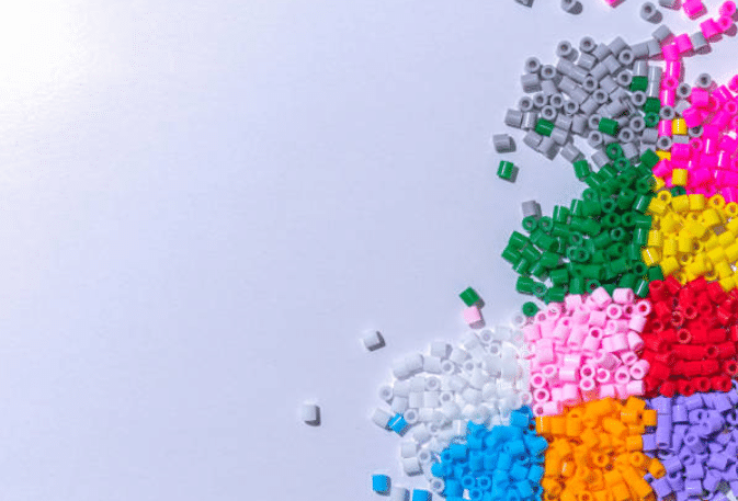 Scattered colorful ABS plastic pellets in white pink green blue orange and red on a white background