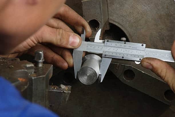 Vernier caliper measuring diameter of machined metal part