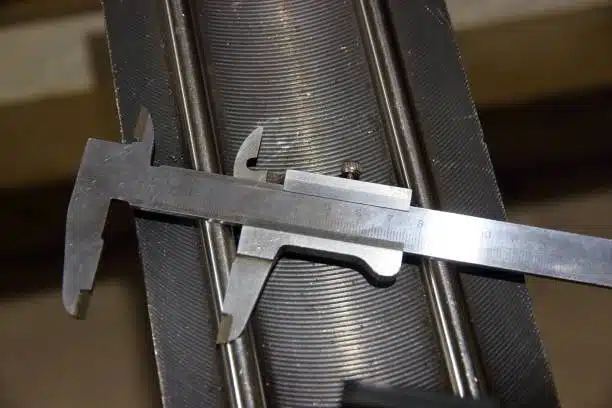 Vernier caliper placed on a threaded cylindrical metal part