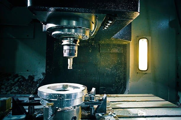CNC vertical milling machine working on a blocky metal component
