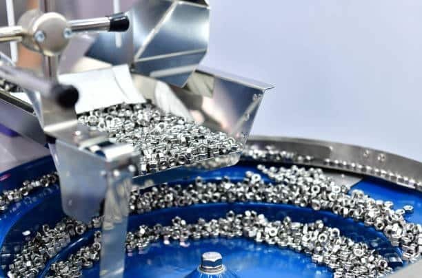 Vibratory bowl feeder sorting small stainless steel nuts for assembly