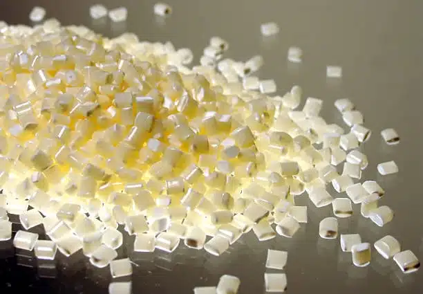 Off-white ABS plastic granules reflecting light, showing purity and safe formulation.