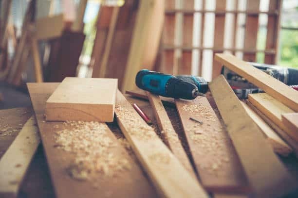 Electric drill and scattered wood planks on a carpenter’s bench