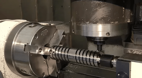 CNC machining of metal shaft using rotary axis and vertical spindle tool.
