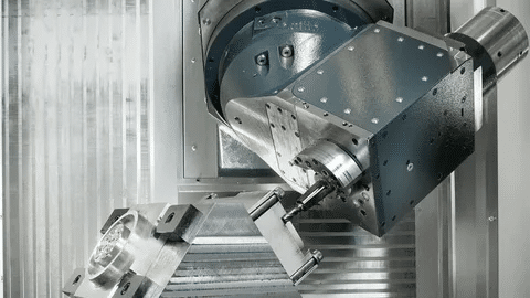 5-axis CNC machine cutting aluminum with angular spindle head movement.