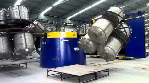 Carousel rotational molding machine with multiple biaxial arms rotating molds for plastic product manufacturing.