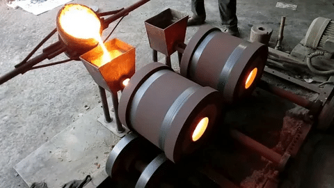 Centrifugal casting process with molten metal poured into cylindrical molds rotating at high speed.