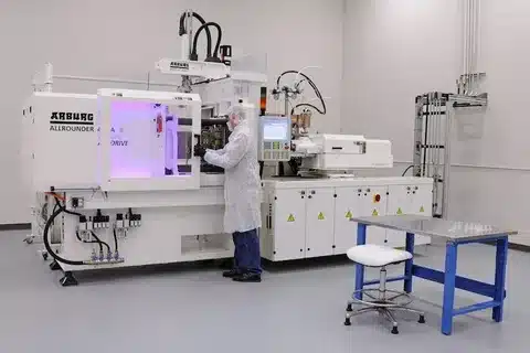 Operator working with high-precision injection moulding machine inside a clean manufacturing environment