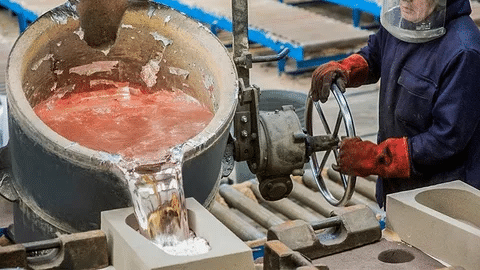 Metal casting process with molten metal poured from a ladle into pre-prepared molds.