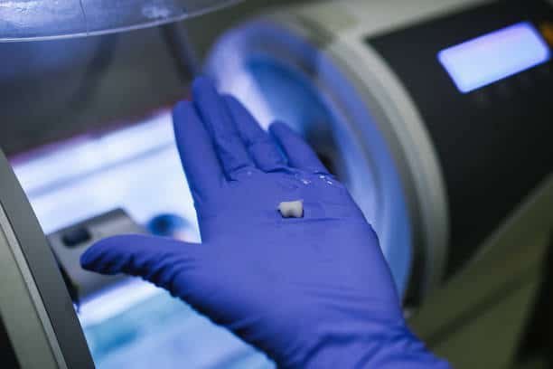 Technician displaying a micro-machined part for medical implant application