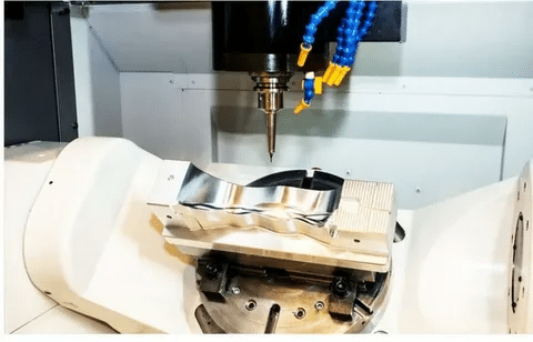 5-axis CNC mill executing precision machining on contoured aluminum surface.