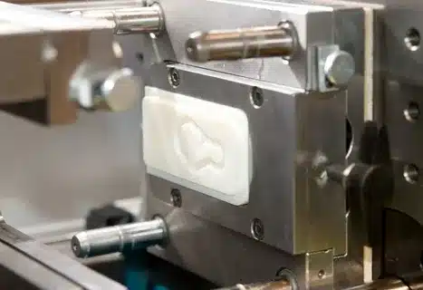 Close-up of an injection molding tool with white plastic part formed inside