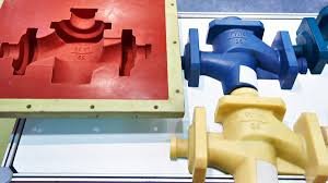 Colorful molded plastic components next to an open cavity mold used in plastic part manufacturing
