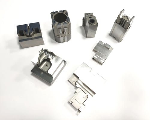 Various CNC-machined steel mold inserts for electrical and electronic parts arranged on a white surface.
