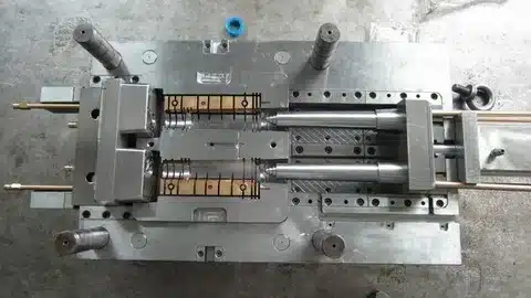 Opened steel injection mould showing core and cavity inserts with cooling channels
