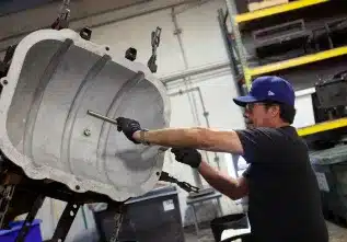 Worker inspecting and assembling aluminum mold before rotational molding production.