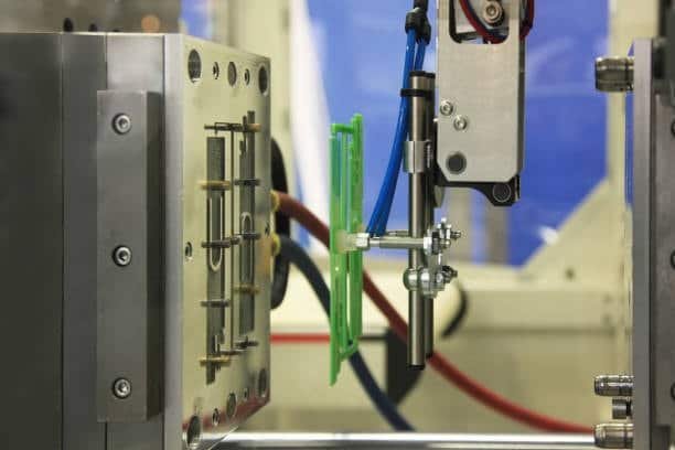 Robotic arm placing insert during overmolding process in a precision mold
