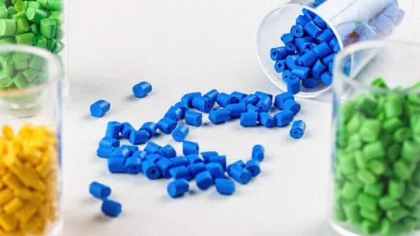 Blue, green, and yellow plastic resin pellets scattered from jars