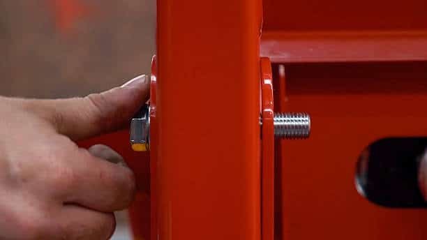 Close-up of a hand tightening a bolt in a red structural joint