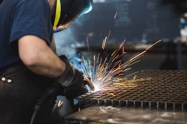 Welder performing close-up welding work on a steel grid
