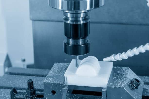 CNC milling machine cutting a white plastic component