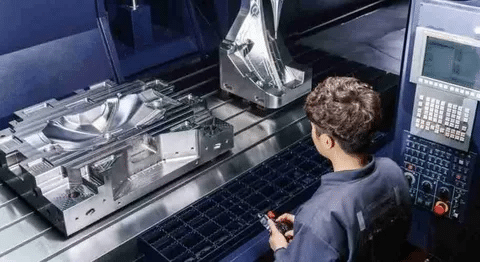 CNC operator working on a large complex mold, increasing machining cost