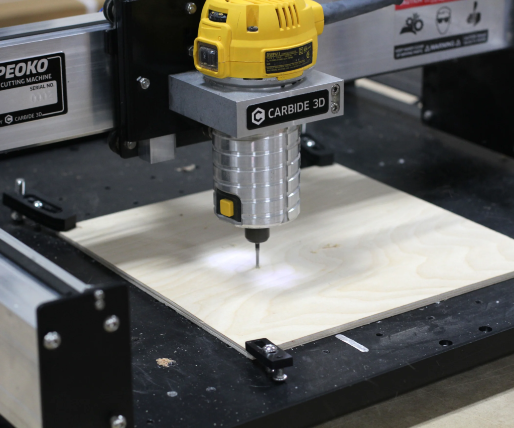 Compact CNC router cutting plywood sheet held by edge clamps