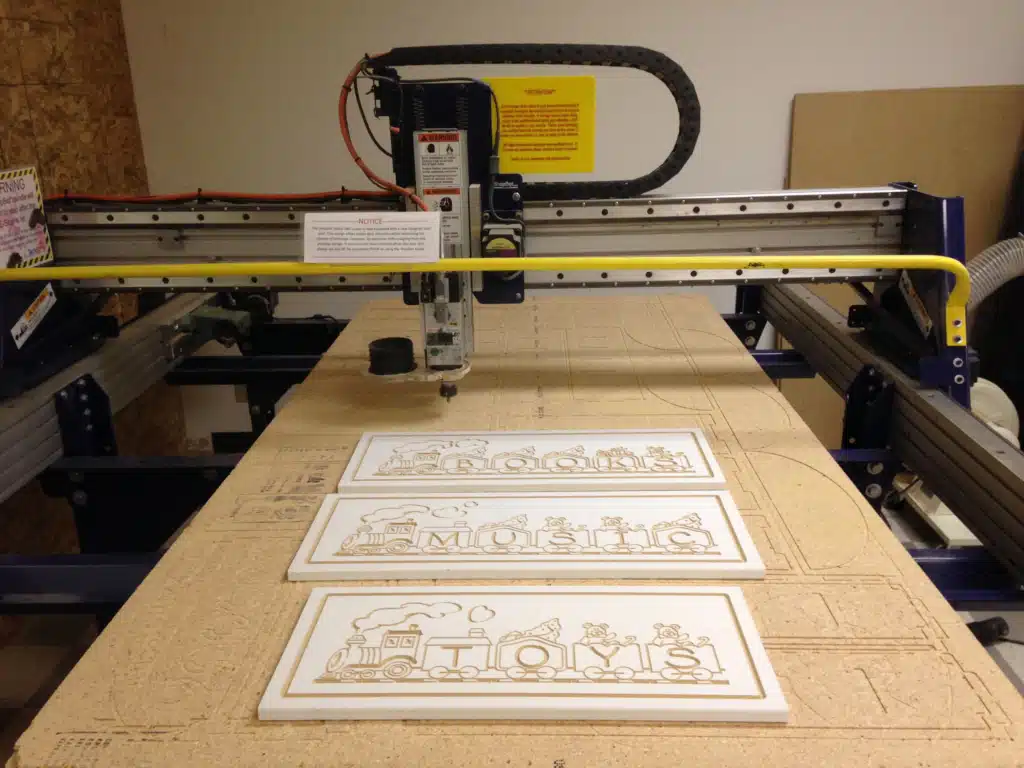 CNC router engraving MDF signage panels using manual clamps for stability