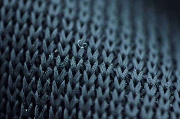 Knit line defect visible on dark molded plastic material showing flow front merge