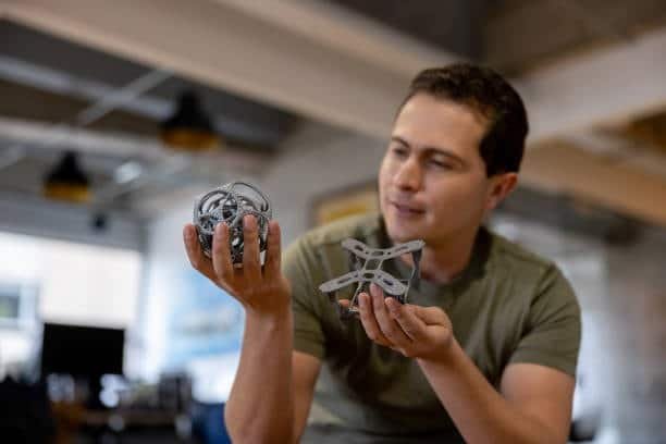 Man holding and inspecting two different 3D printed plastic parts
