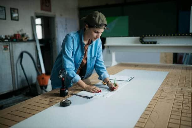 Woman marking layout lines on plastic sheet for CNC machining