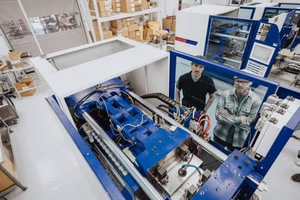 Engineers inspecting operation of injection molding machine