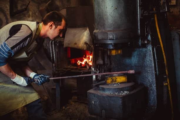 Forging process with visible furnace and red-hot metal under press
