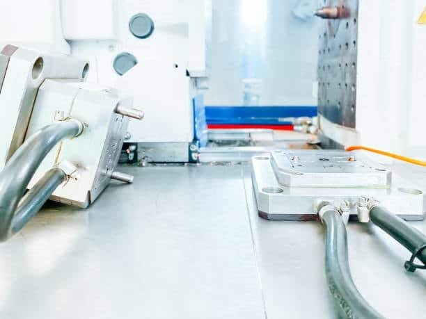 Injection mold installed on machine base with visible hydraulic and electrical connections
