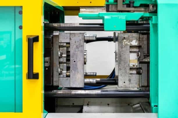 Injection molding machine showing mold halves opened during insert setup
