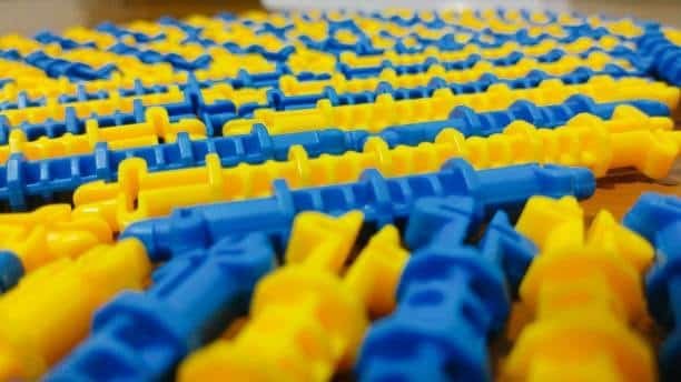 Yellow and blue injection molded parts with visible seam lines from knit defects