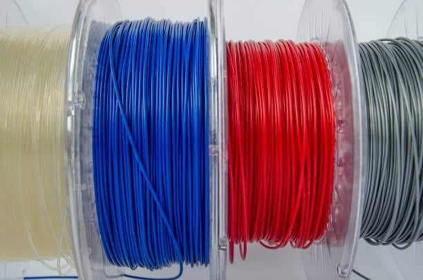 Spools of nylon and Delrin filaments in various colors for 3D printing and plastic manufacturing