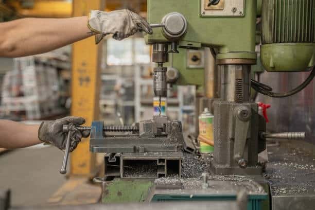 Manual drilling machine with operator adjusting workpiece for machining