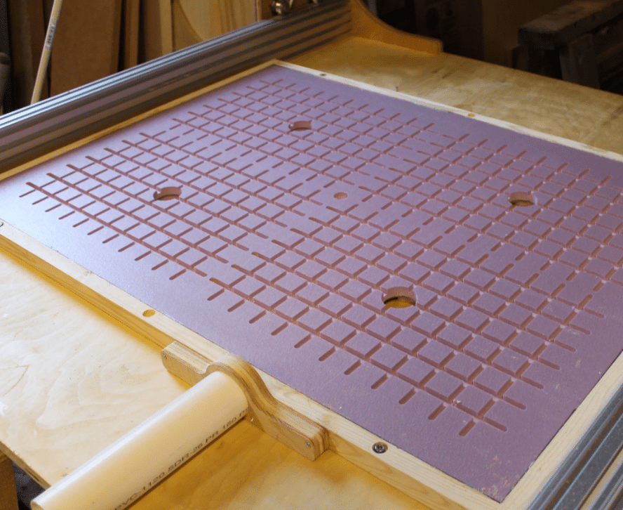 Close-up of pink foam CNC vacuum board with channels and suction zones