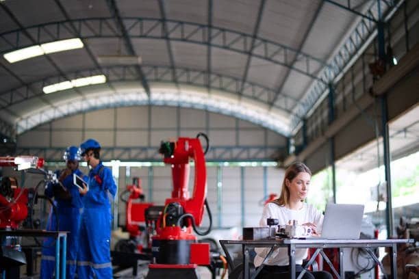 Engineer supervising robotic welding systems in a modern facility