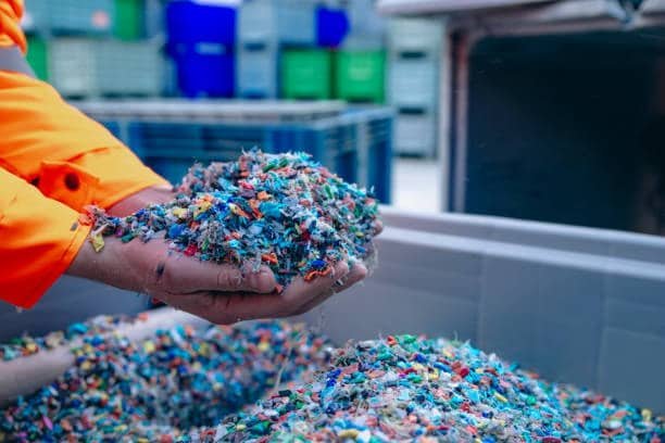 Worker handling shredded plastic for molding applications