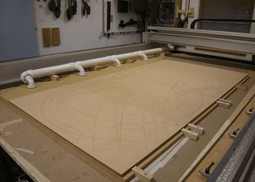 ustom vacuum table design featuring white PVC piping across CNC surface