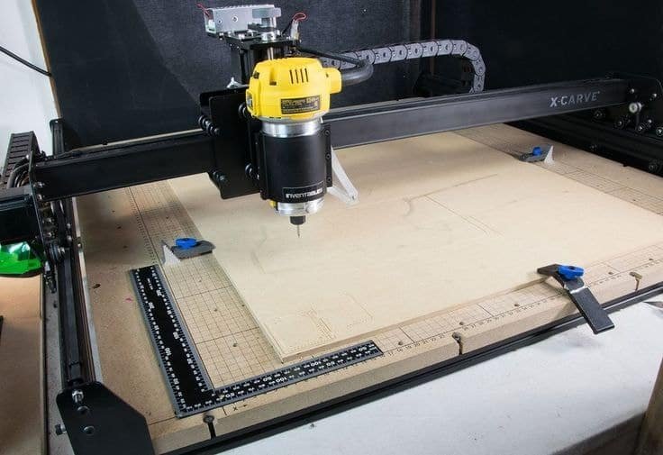 X-Carve CNC router using manual edge clamps to secure MDF sheet