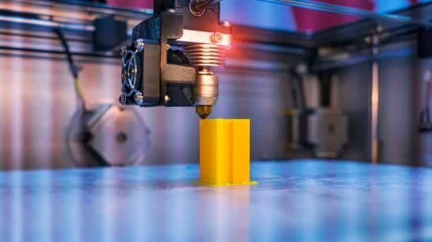 FDM 3D printer printing yellow plastic part on heated bed with nozzle extrusion