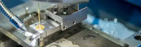 Close-up of wire EDM machine setup showing the wire and workpiece alignment