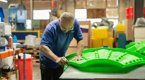 Worker finishing a custom molded plastic product in a factory