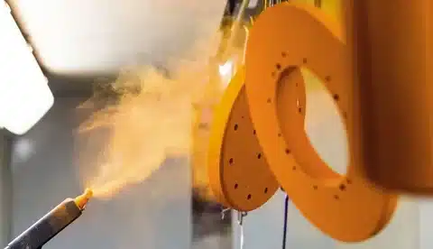 Powder coating spray process adding blue finish to aluminum part.